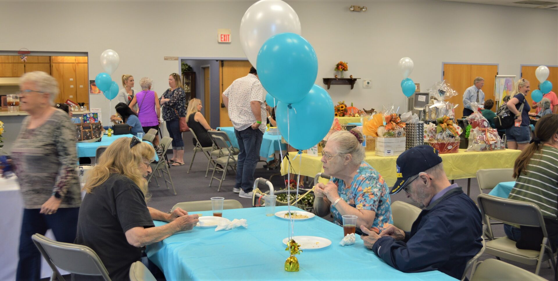 party with people sitting for mean with white and blue balloons