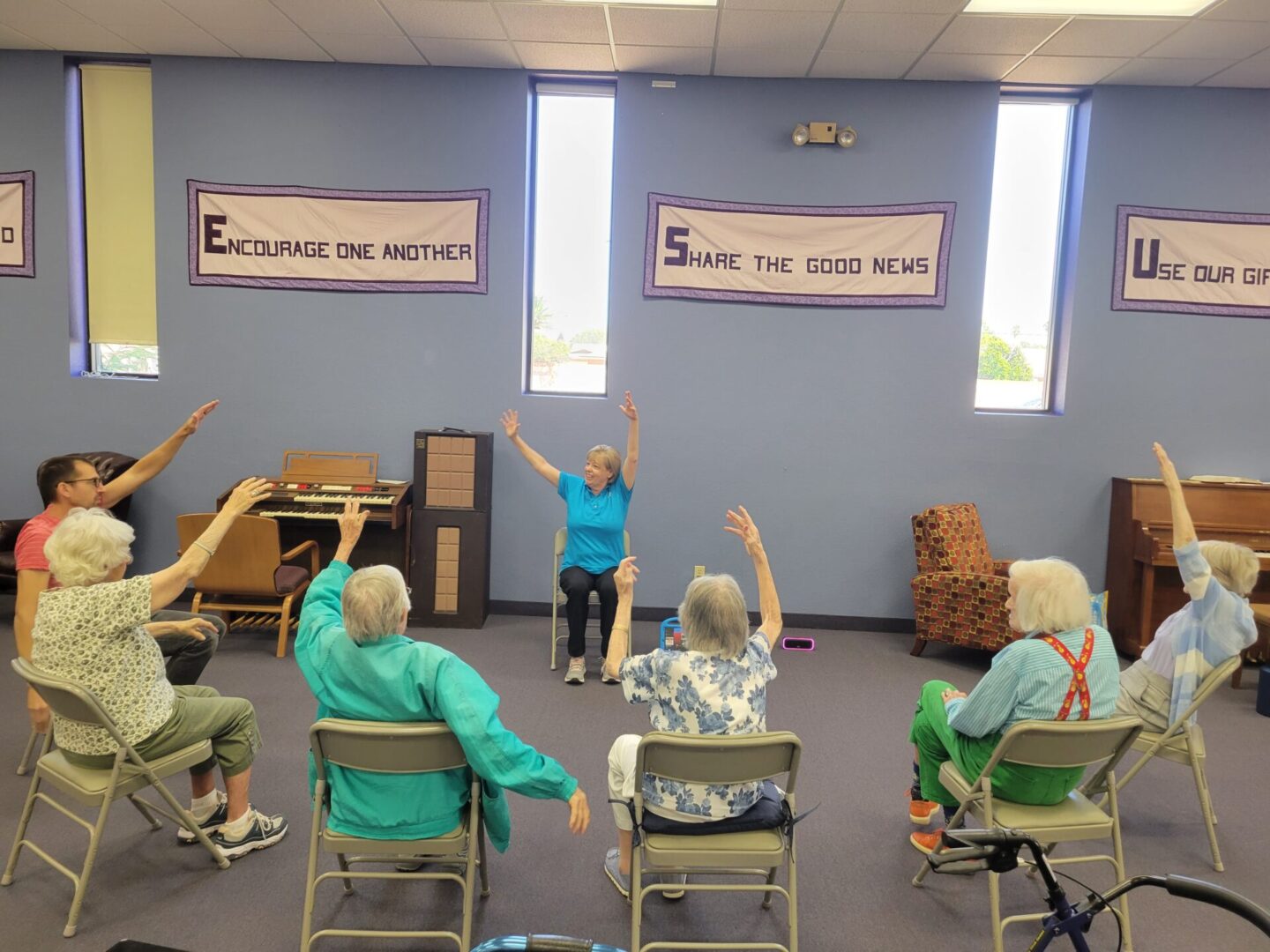 All old people sitting on chairs and raising their hands