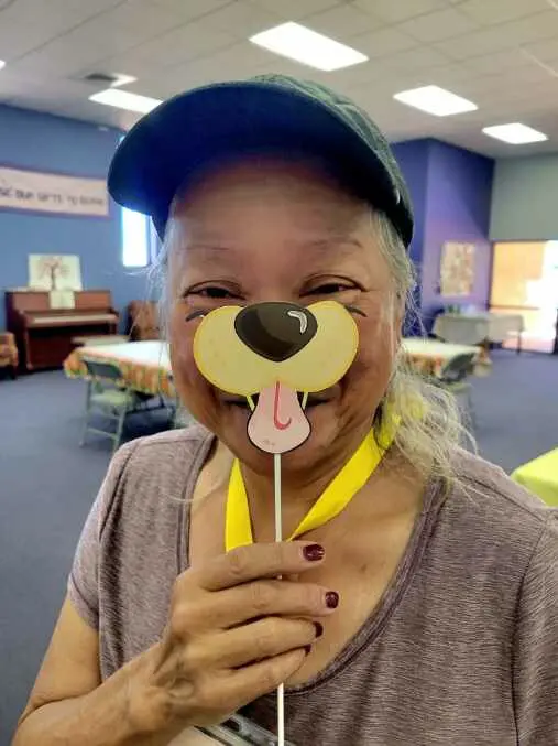 An older woman holding a DOG'S nose prop stick